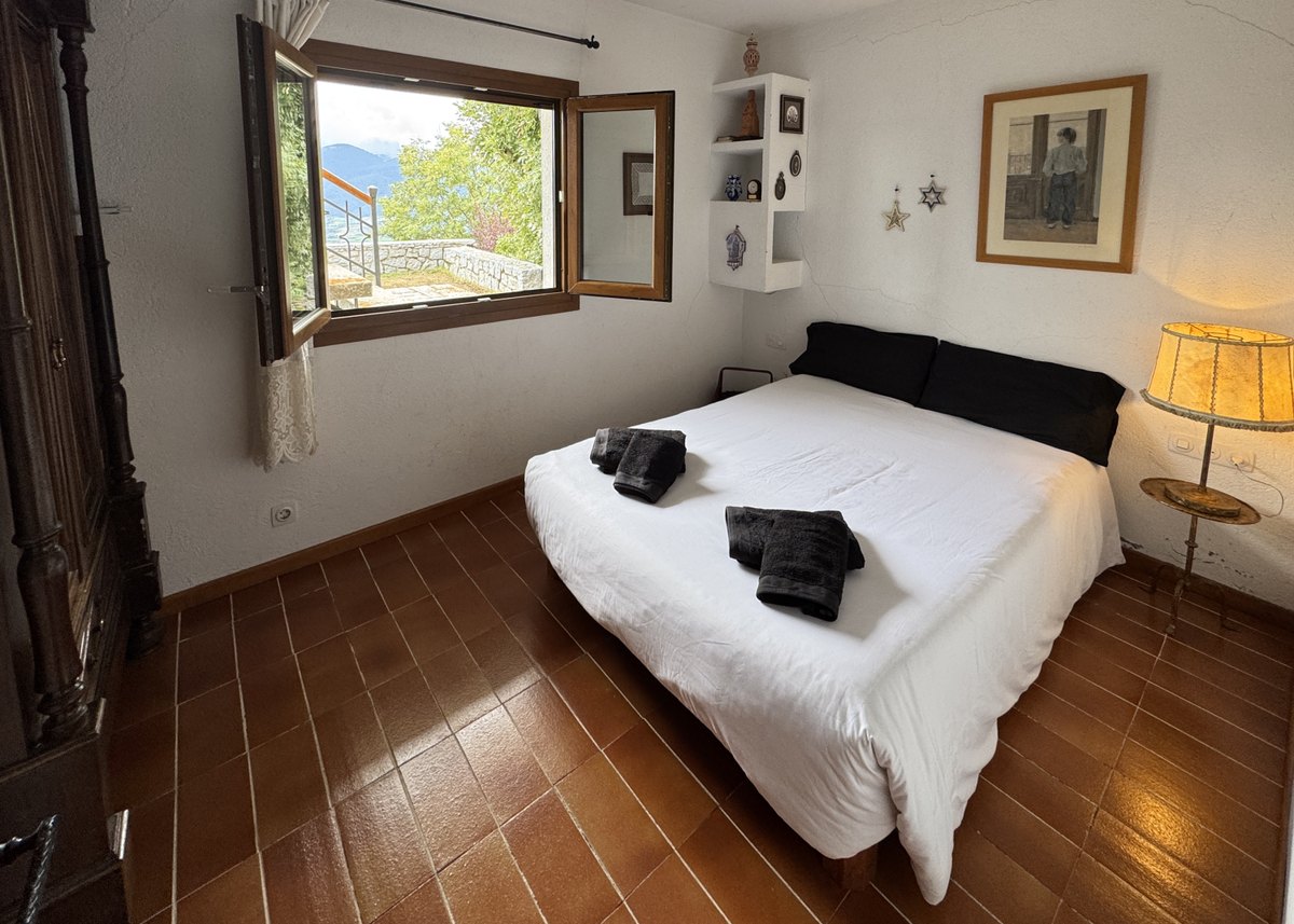 La habitación doble, con la cama hecha de blanco y la ventana abierta al jardín