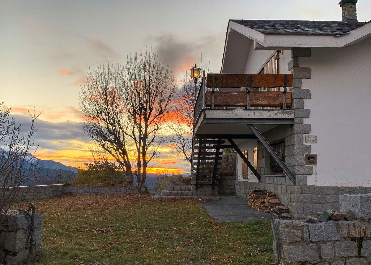 La casa al atardecer, con el balcón de madera y la escalera exterior