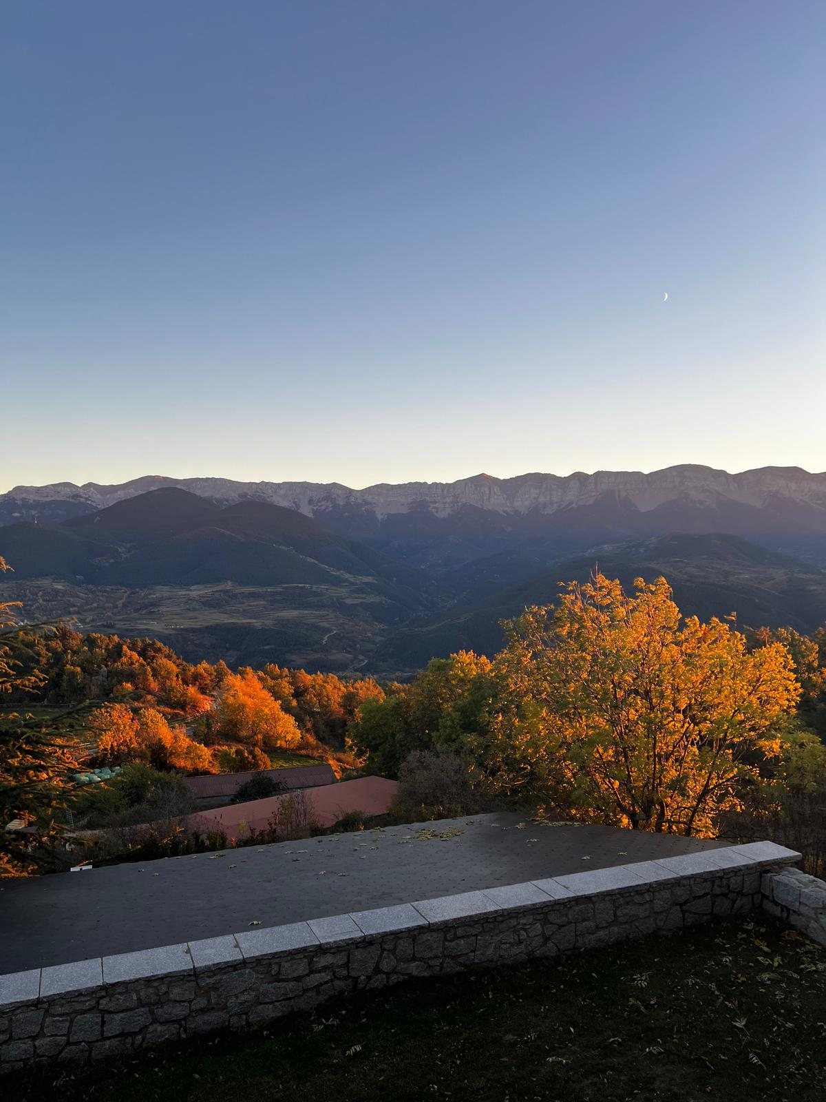 La sierra del Cadí al atardecer, con los árboles del valle dorados por el otoño y la luna creciente