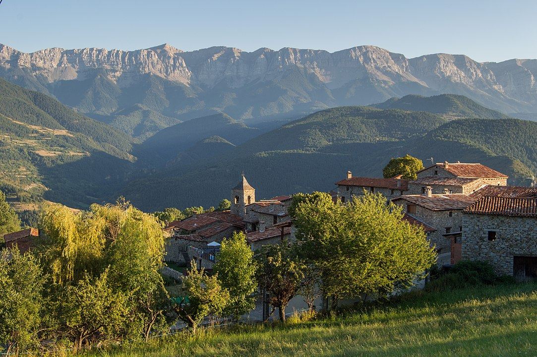The village of Travesseres among meadows, with the mountain behind